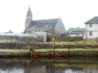 Hamnen i Ardrishaig. Nedanfr kyrkan ligger ett vikingaskepp frtjt.